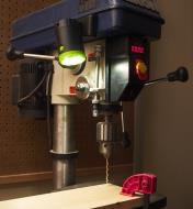 A rechargeable clip light magnetically mounted to the side of a drill press to light the machine table