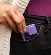 A woman slips an LED pocket magnifier into the front pocket of her pants