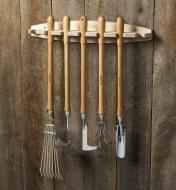 Five garden tools hanging on a Lee Valley garden tool rack mounted on a barnboard shed wall