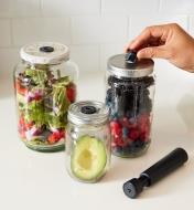 Half an avocado, berries and salad stored in jars using the Airtender system