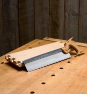 A dovetail saw leaning against a board on a workbench