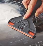 Using a razor blade in a wide holder to scrape a ceramic cooktop