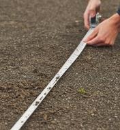 Using a washable tape measure to take a measurement on bare ground