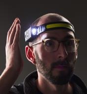 A man wearing a COB headlamp waves his hand near the motion sensor to activate one of the side beams