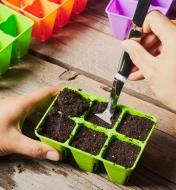Tamping down soil in a six-cell seed starter