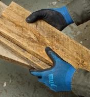 Wearing mud gloves while holding planks of wood