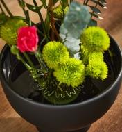 Flowers inserted into the Blue Ribbon flower holder that has been placed in a round black vase