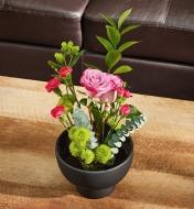 A flower arrangement in a black vase sits on a coffee table