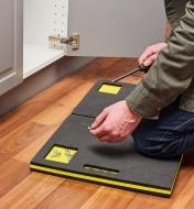 Man kneeling on a kneeler while holding a screw in one hand and a screwdriver in the other