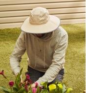 A kneeling gardener wearing the wide-brim hat while tending to some flowers