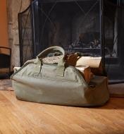 A Lee Valley Firewood Tote filled with wood sits on the floor next to a fireplace