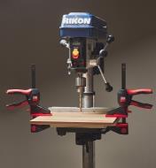The 360 degree trigger clamps are clamping a piece of wood to a drill press