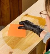 Applying Osmo 2K wood oil to a board with a plastic spreader
