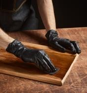A woodworker wearing gloves uses a pad to apply Rubio Monocoat 2C to a plank of wood