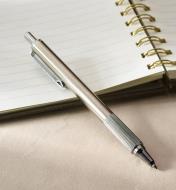 The stainless-steel pen sits on an opened spiral notebook