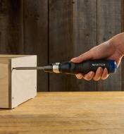 Using a 10-in-1 ratcheting screwdriver to tighten a screw in a plywood box
