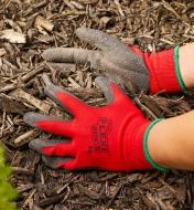 Spreading mulch on a garden bed while wearing Flex Grip gloves