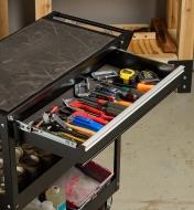 The drawer on a workshop tool cart opened, showing several small hand tools stored inside