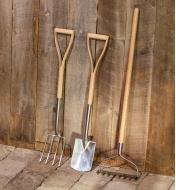 The set of three children’s garden tools standing up against a wooden fence