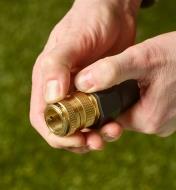 Thumbs push down onto a brass female quick coupler on the end of a hose
