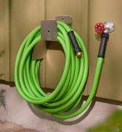Garden hose hanging on the side of a house while attached to an outdoor tap
