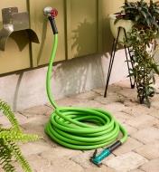 Garden hose coiled up on the ground with the end attached to an outdoor tap