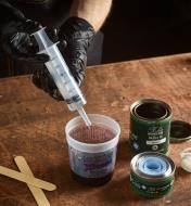 A woodworker uses the syringe to transfer wood finish into a container