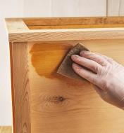 Using a sponge to apply Everlasting Oil to a wooden box