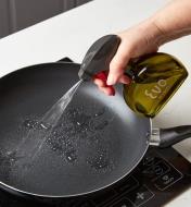 Using the oil sprayer to spray oil onto a frying pan