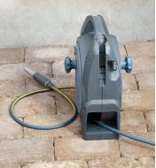 The manual hose reel sits on a patio while the hose lies next to it