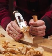 A woodworker uses an E.C. Emmerich Primus smooth plane on a cherry-wood board