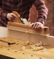 A woodworker edge-jointing a large maple board with an E.C. Emmerich traditional wooden try plane