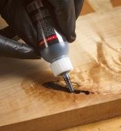 Applying Starbond Black CA Glue to a crack in a wood surface