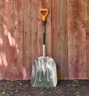 A Fiskars scoop shovel leaning against fence boards