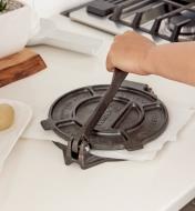 Flattening a ball of dough by pushing down on the handle of the tortilla press