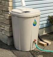 A man uses water from the rain barrel to water a potted plant