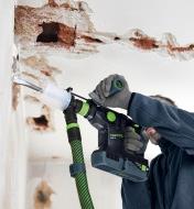 Drilling into drywall using a hammer drill with a dust extractor attached