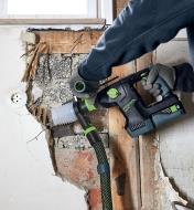 Removing a piece of drywall using a hammer drill with a dust extraction adapter attached