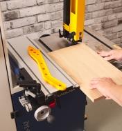 A woodworker rip-cuts a board on a bandsaw, using a Laguna DX3 Driftmaster fence to guide the cut