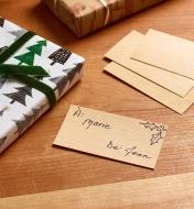 Cartes professionnelles en bois, dont une avec des écritures, posées sur une table, près de cadeaux emballés