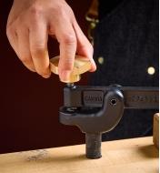 A hand tightens the brass clamping knob on the Veritas Hold-Down