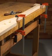 A rough-cut canoe paddle held to a benchtop with FA bar clamps