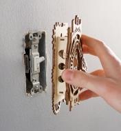 Placing the gears and lever light switch cover onto a toggle light switch