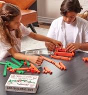 Two children sitting at a table playing with the 37-piece wooden log set