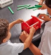 Children building a log cabin using the 37-piece log building set