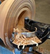 A Bowlsaver Max4 cutter guided on the turntable base as it cuts into a wooden bowl-turning blank