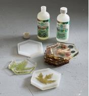 Bottles of epoxy resin and hardener next to three cured epoxy coasters and a coaster still in a mold