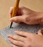 Using a skew chisel to carve a design into the linoleum linocut block