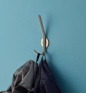 A jacket and a backpack hang on the two bottom hooks on a stainless-steel triple hook