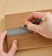 Using a cabinetmaker’s rule and pencil to mark a line on wood.